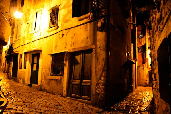 A narrow cobbled street in Rovinj's old town at night.