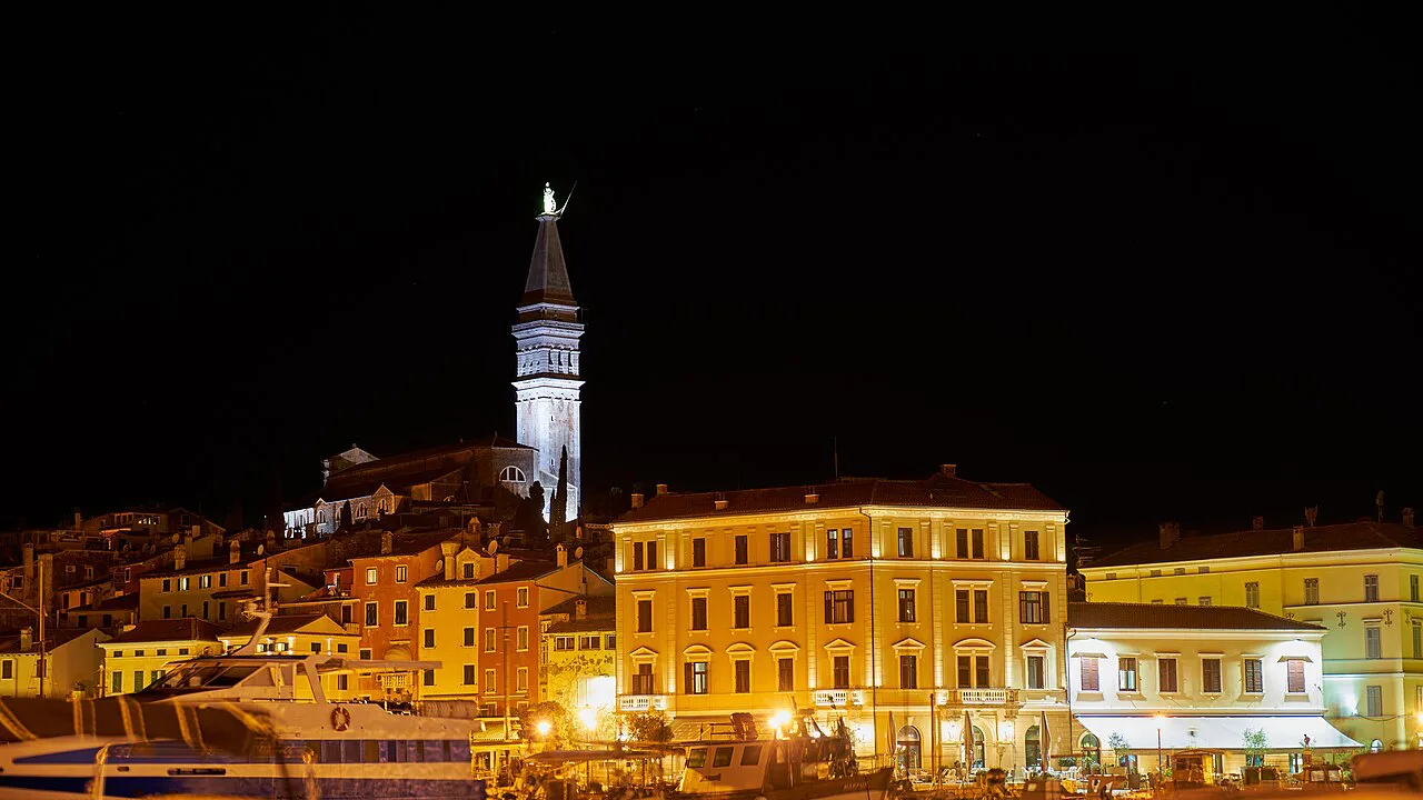 Rovinj's lit waterfront and bell tower at night.