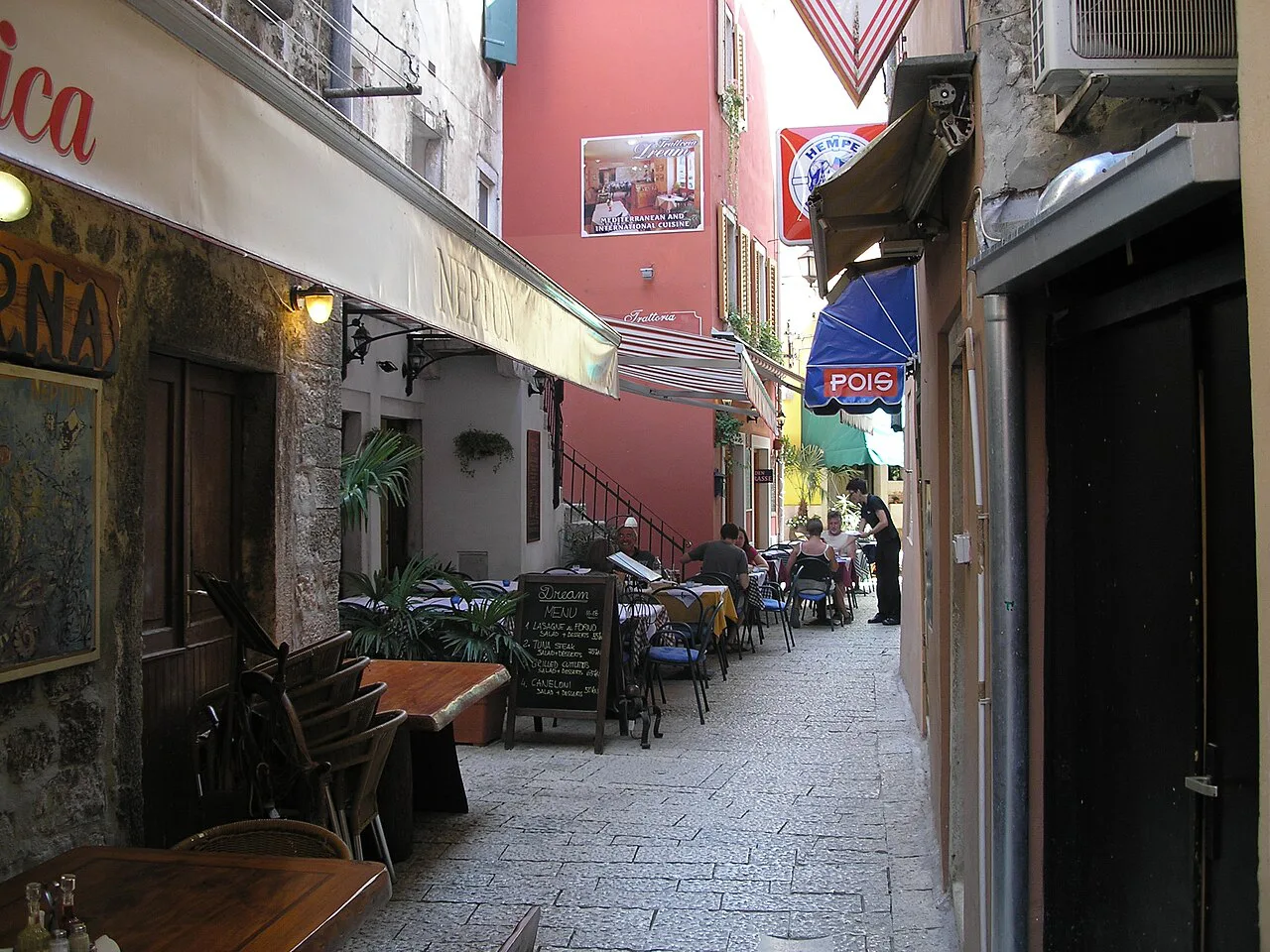 A narrow old-town street with café tables, Rovinj.