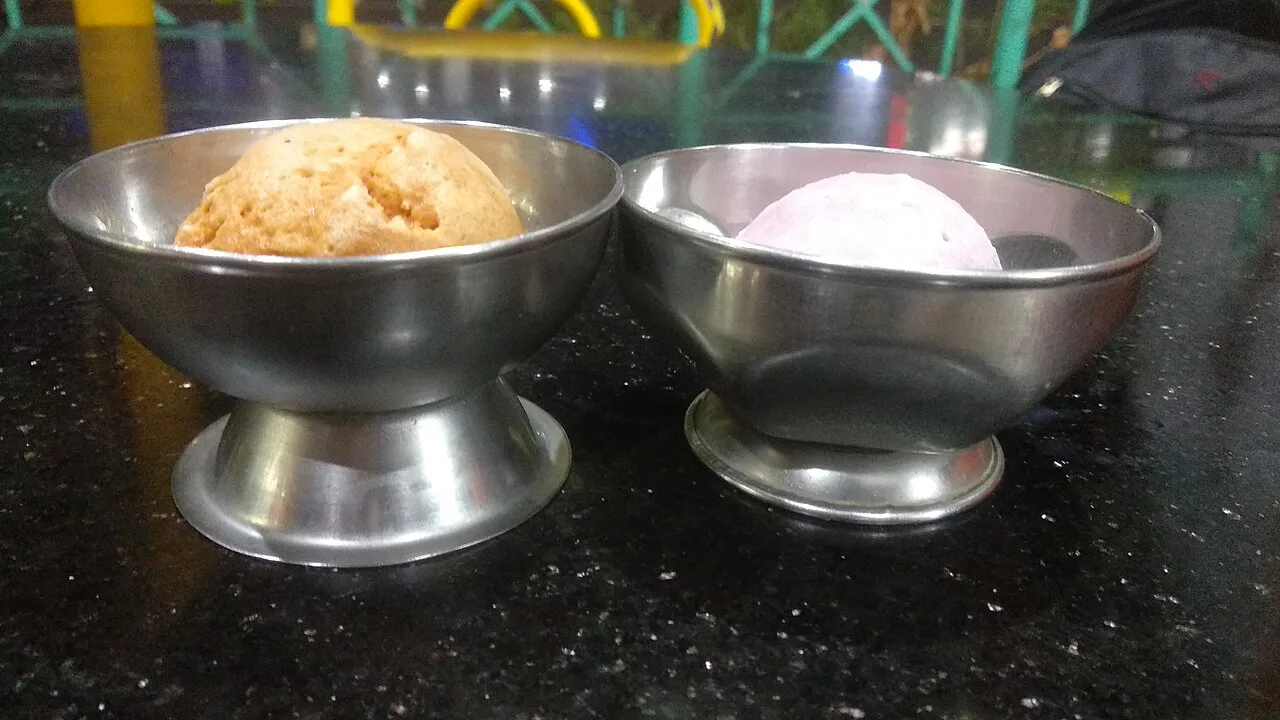 Two scoops of ice cream in metal cups.