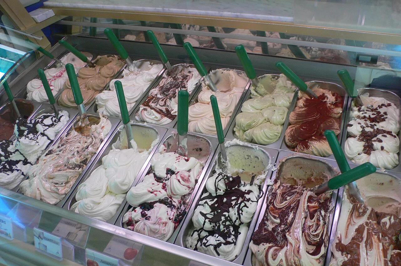 A gelato counter with chocolate and cream flavours.