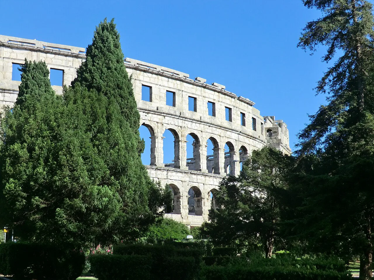 Pula Arena framed by trees.