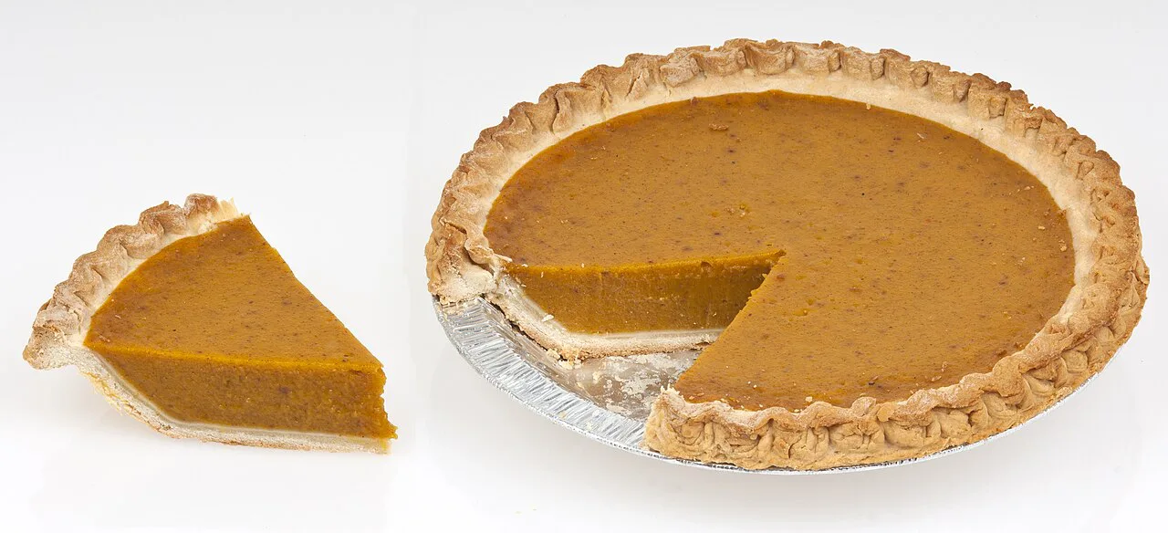 A pumpkin pie with a slice cut out.