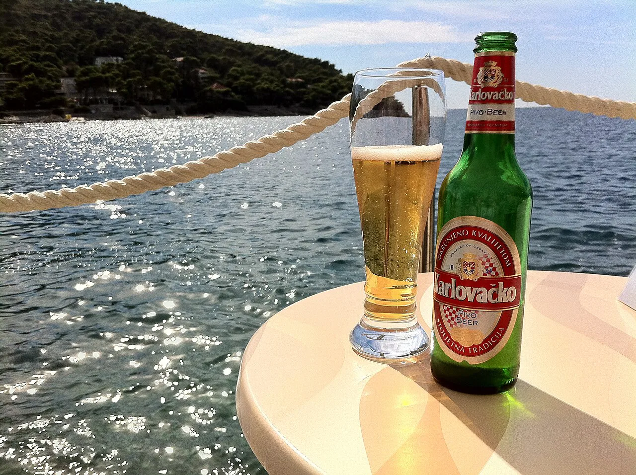 A bottle and glass of Karlovačko beer by the sea in Dubrovnik.