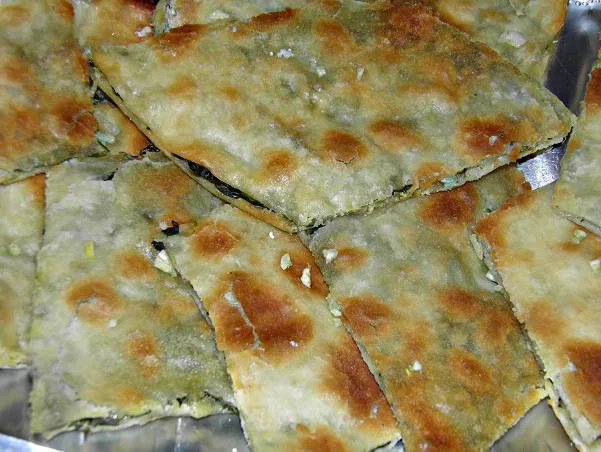 Diamond-cut pieces of soparnik topped with garlic.