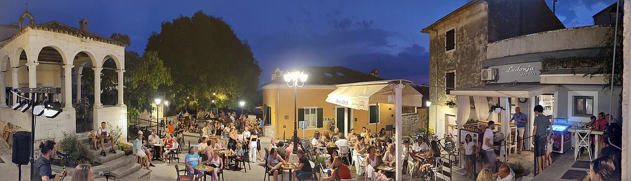 Busy café terraces on a square in Rovinj at dusk.