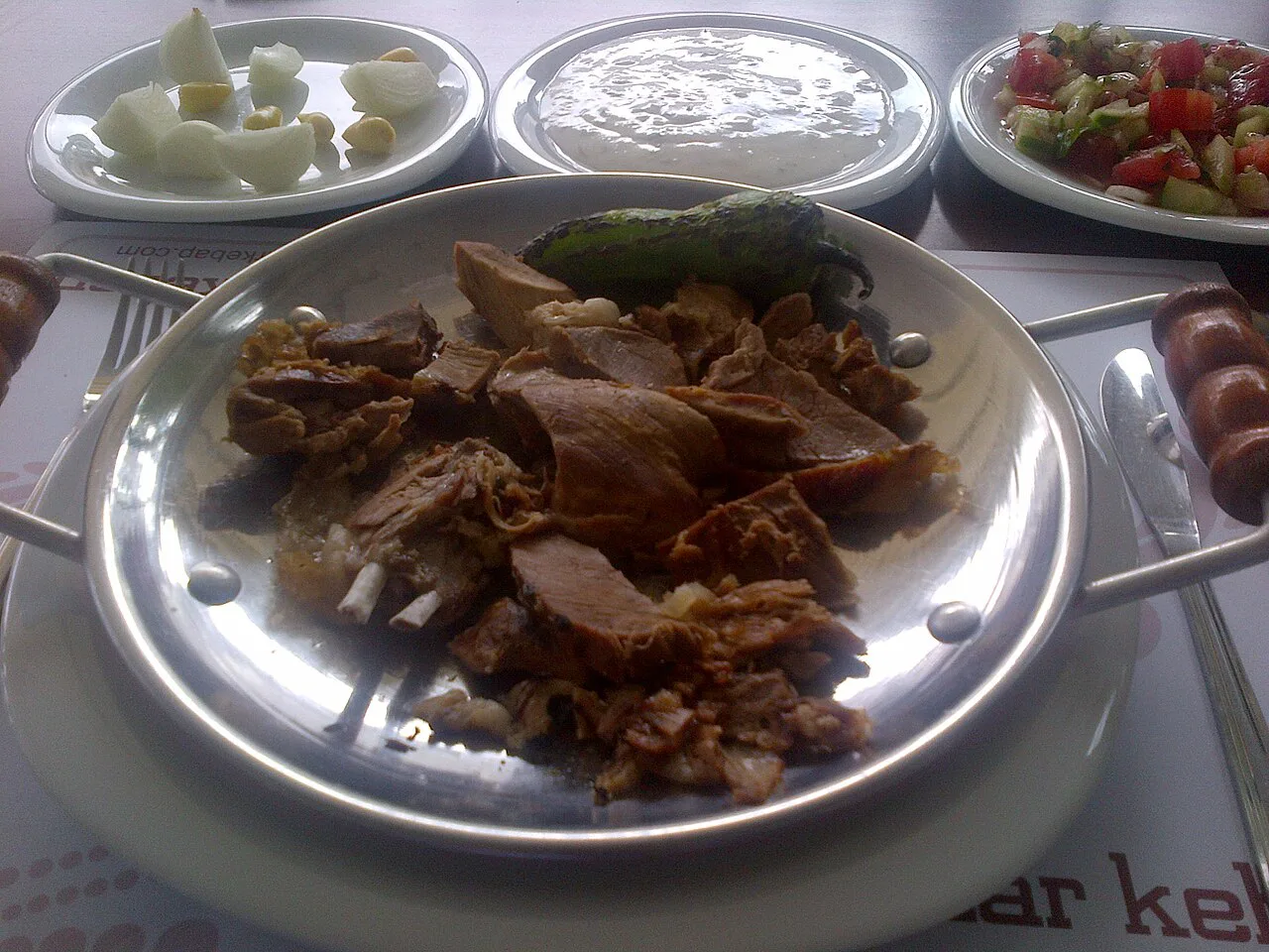 Spit-roasted lamb served with side dishes.