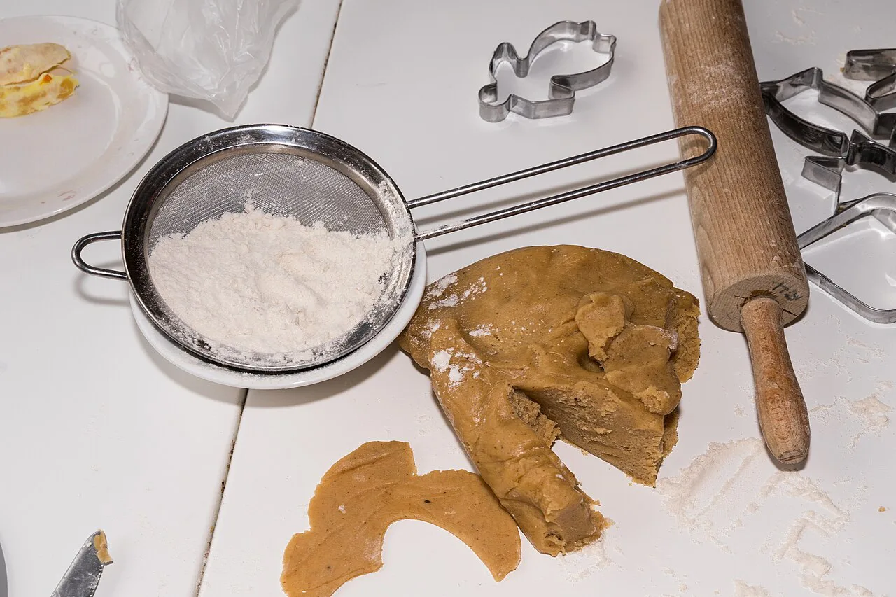 Spiced biscuit dough with cutters and a rolling pin.