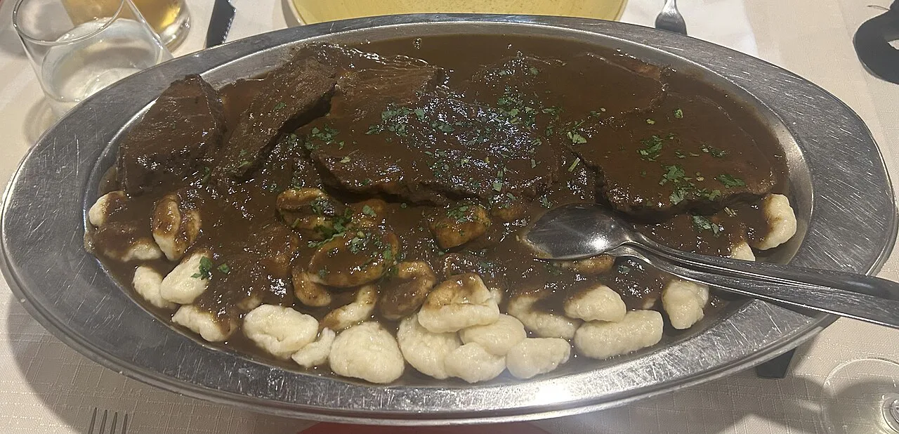Pašticada with gnocchi in a metal dish.
