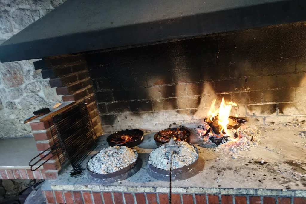 Peka lids cooking under hot embers in an open hearth.