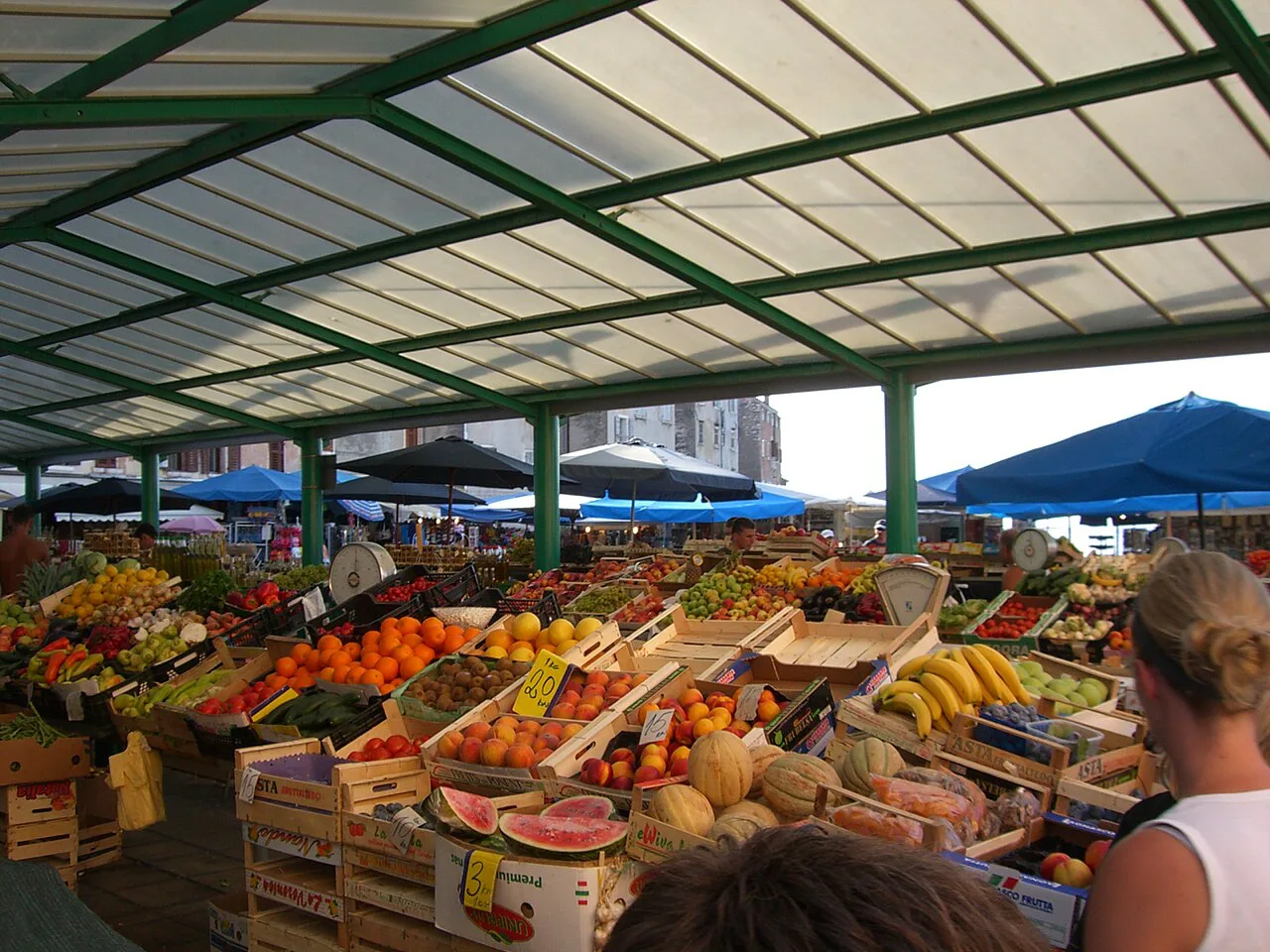 Produce stalls under the canopy of the Rovinj market.