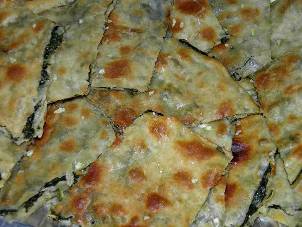 Diamond-cut pieces of soparnik topped with garlic.
